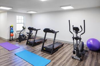 A gym with exercise equipment and yoga mats